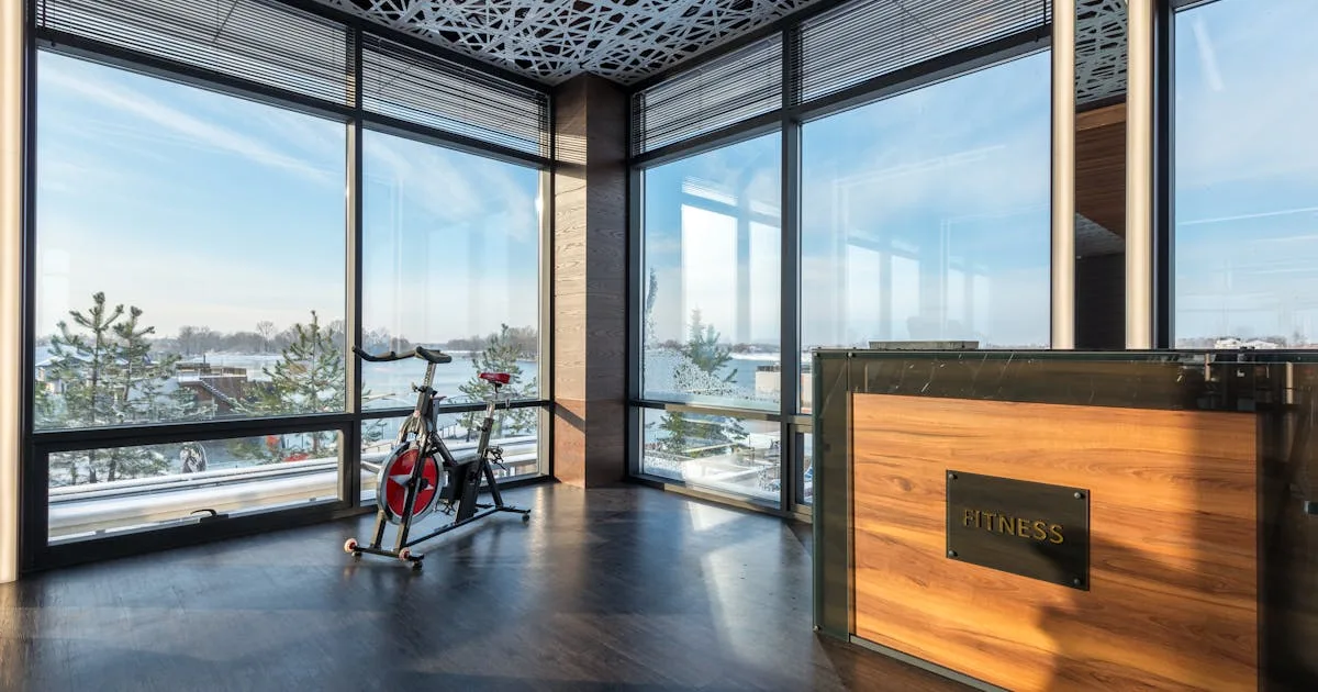 Two people in athletic clothing are smiling and looking at a tablet in a gym