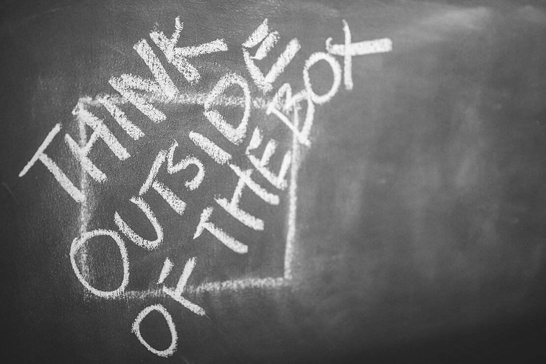 Words "Think Outside the Box" written on top of box drawn on chalkboard