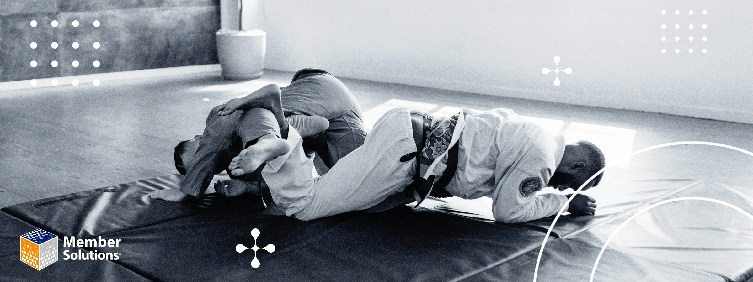 A black-and-white image of two people practicing Jiu-Jitsu in a gym