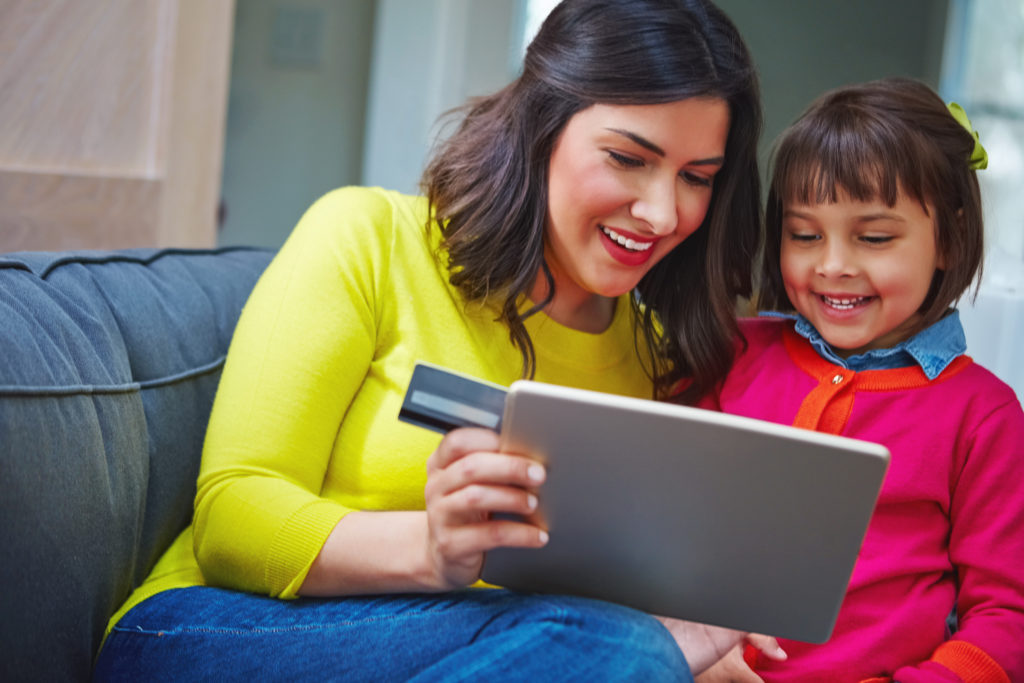 Shot of a mother and daughter using a credit card to pay for event registration with a tablet at home