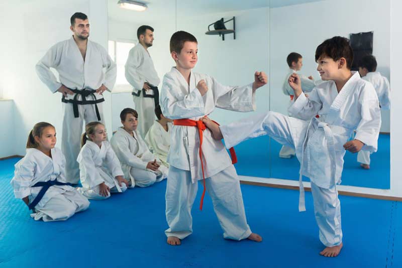 Laughing boys training in pair use karate technique during class