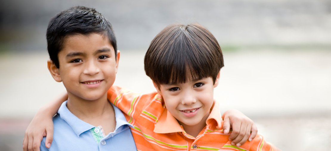 Two smiling kids with hand around shoulder promote anti-bullying