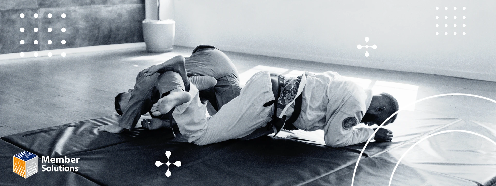 A black-and-white image of two people practicing Jiu-Jitsu in a gym