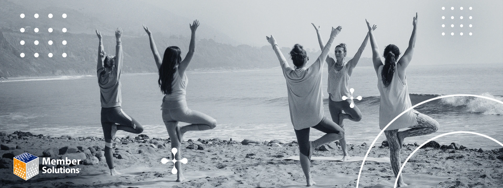 Five women doing yoga outdoors on the beach by the sea