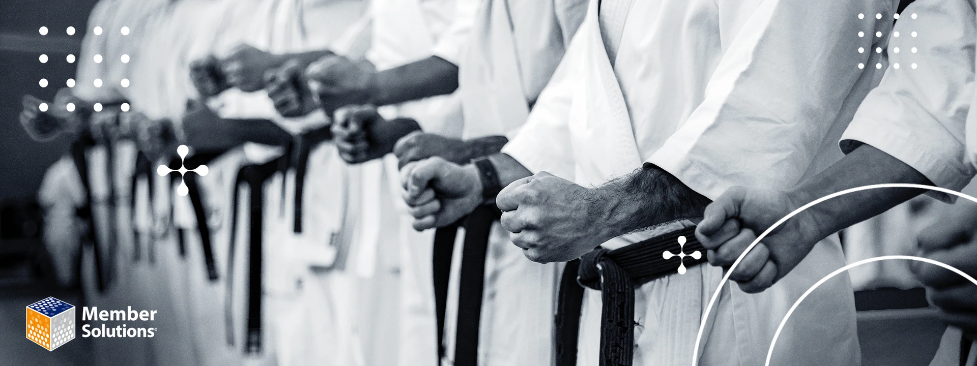 Martial artists in white uniforms and black belts, standing in a row with clenched fists, conveying discipline and unity