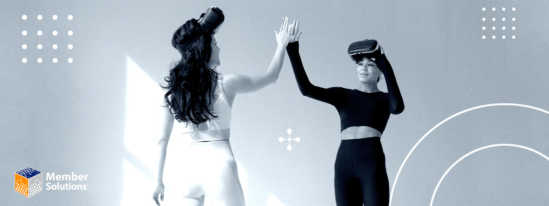 Two women wearing VR headsets high-five in a playful environment