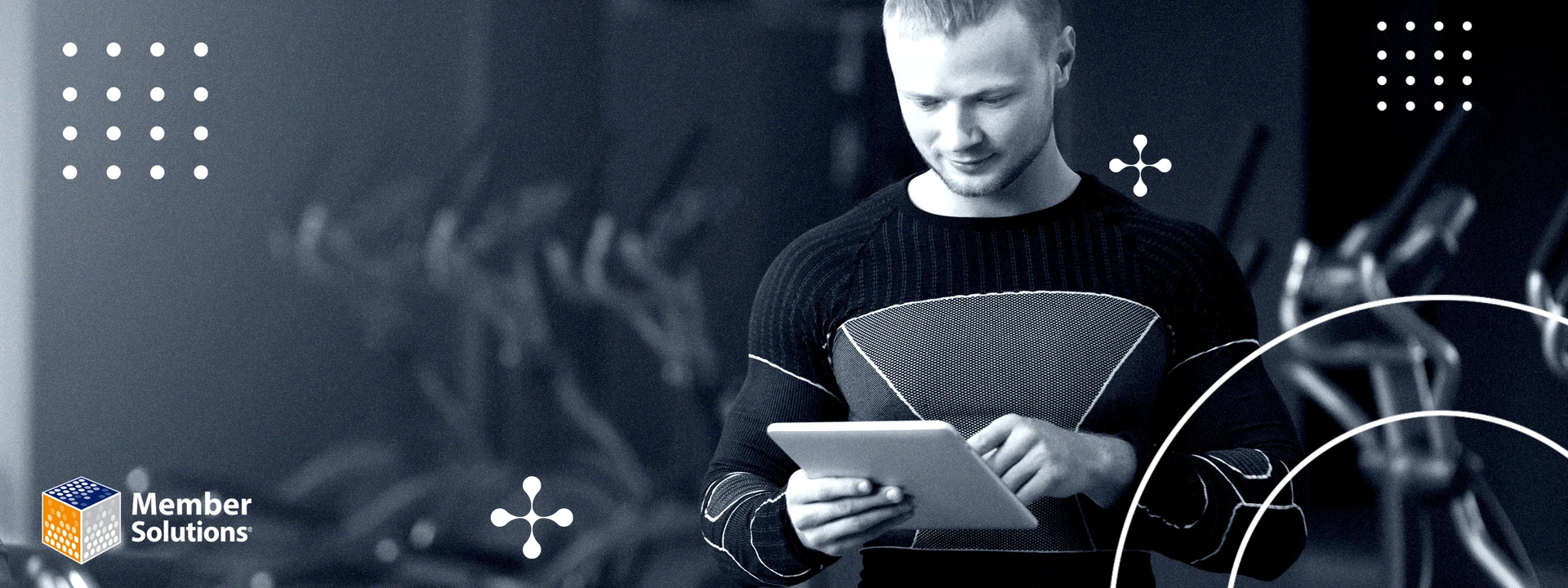 A man in a gym wearing a black shirt uses a digital tablet to write a review